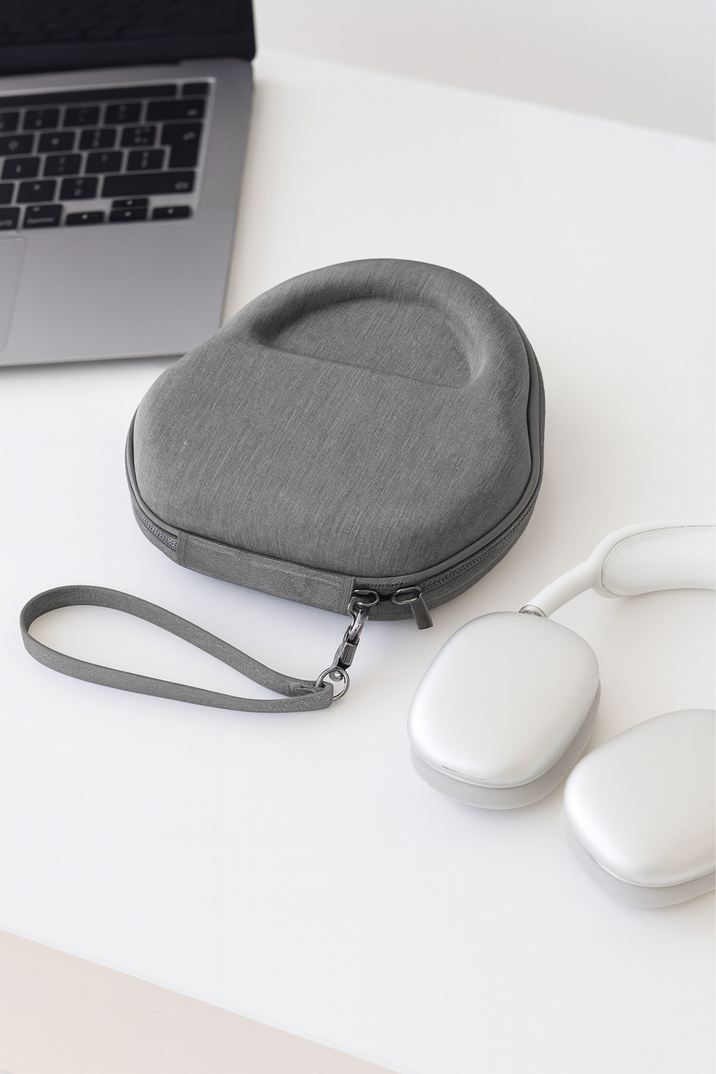 AirPods Max Hardcase auf weißem Schreibtisch neben MacBook und weißen AirPods Max, minimalistisches und modernes Arbeitssetup